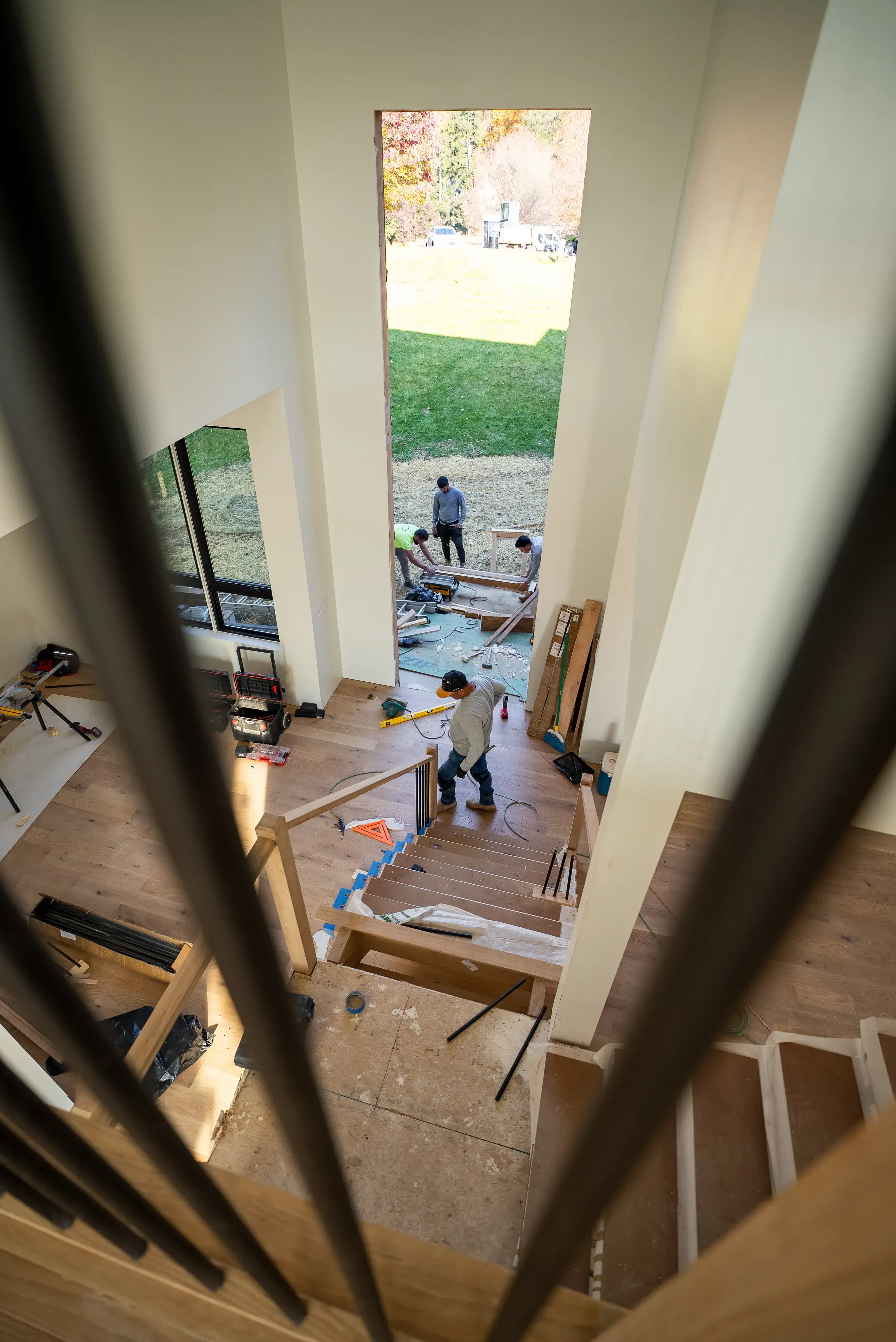 View from above of construction workers assembling a staircase in a modern home, with tools and materials scattered around.