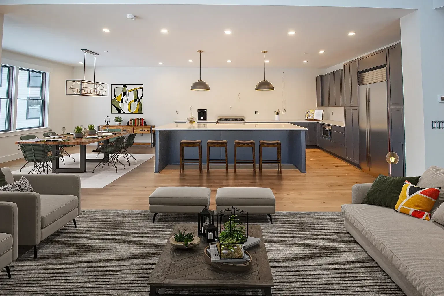 This image showcases a modern and minimalistic open-concept kitchen and living area. The kitchen features a large central island with a sleek, clean design, complemented by pendant lighting. The stools at the island add warmth and a rustic touch. The living area displays cozy seating with earthy accents like terrariums and plants on the coffee table, blending natural elements into the modern aesthetic.